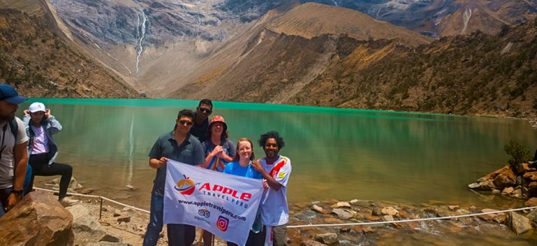 A group of smiling tourists at Humantay Lake