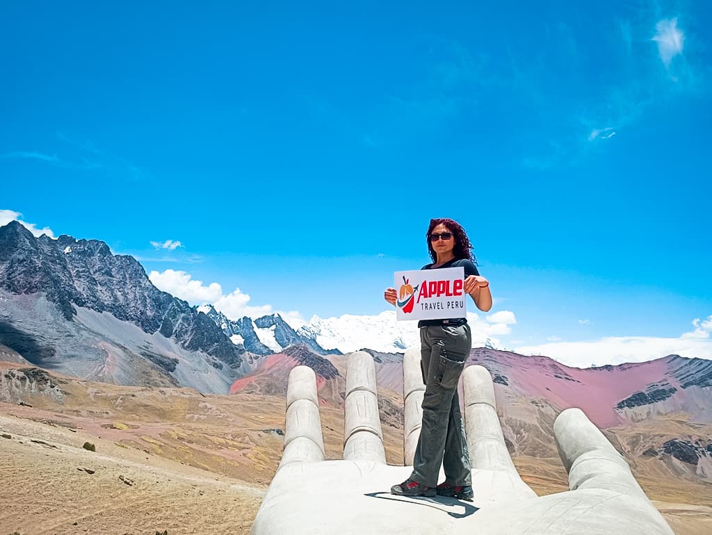 A female tourist with Apple Travel Peru's placard standing at Rainbow Mountain Tour