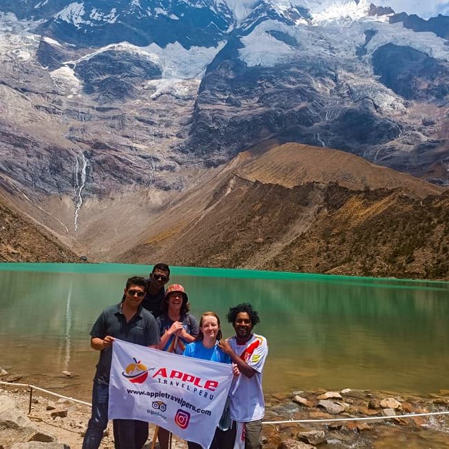 A group of smiling tourists at Humantay Lake