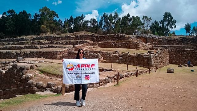A smiling female tourist with Apple Travel Peru's flag during a city tour